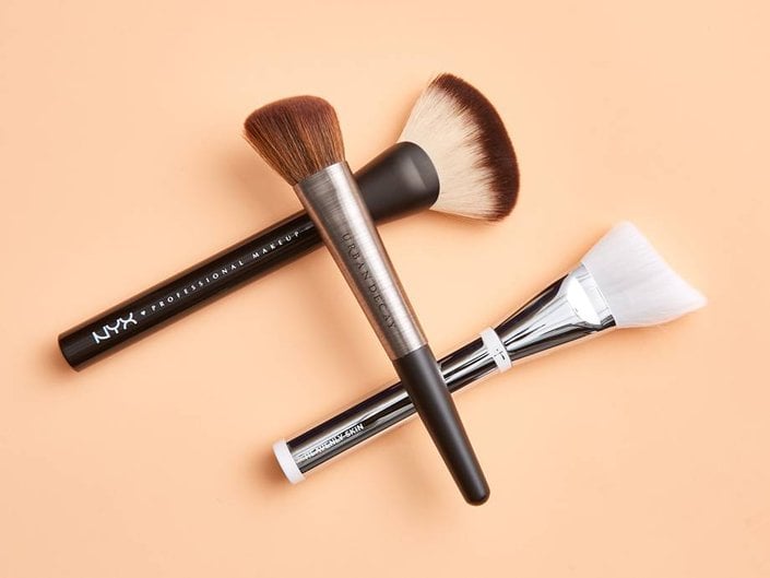 three makeup brushes on a colored background