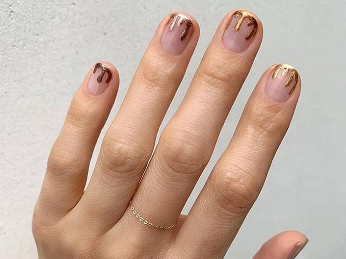 hand with gold dripping french manicure on nails