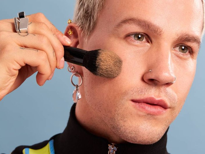 person wearing no-makeup makeup and holding makeup brush to cheek