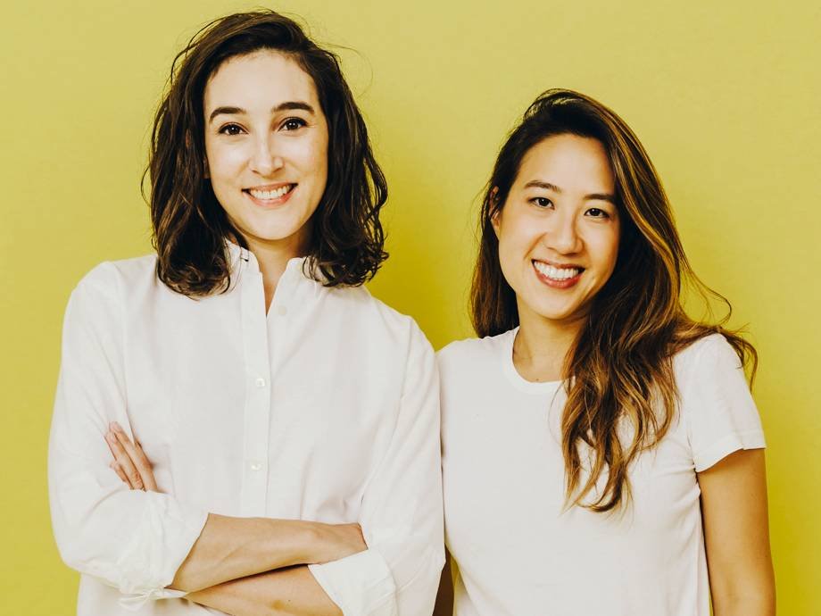 two people wearing white shirts smiling at camera on yellow background