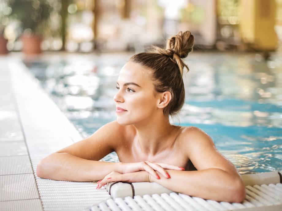 person in pool wearing a top knot and looking away from camera