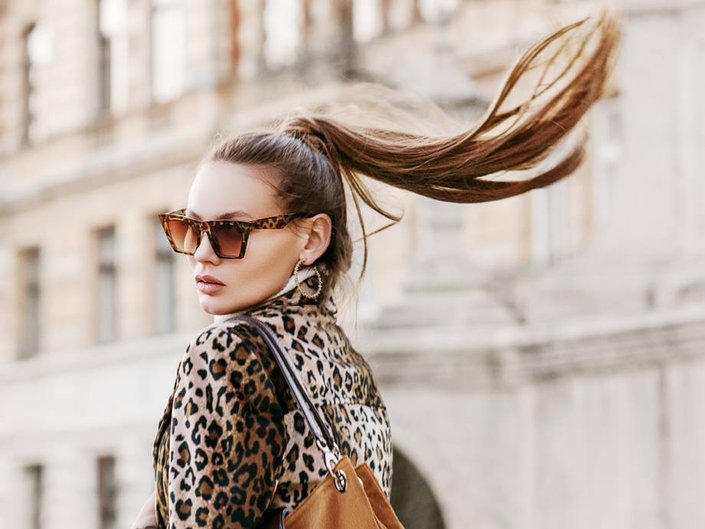 person with a high, long ponytail wearing sunglasses and a leopard jacket