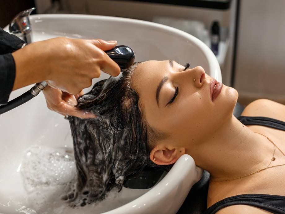 person getting their hair washed in a shampoo bowl