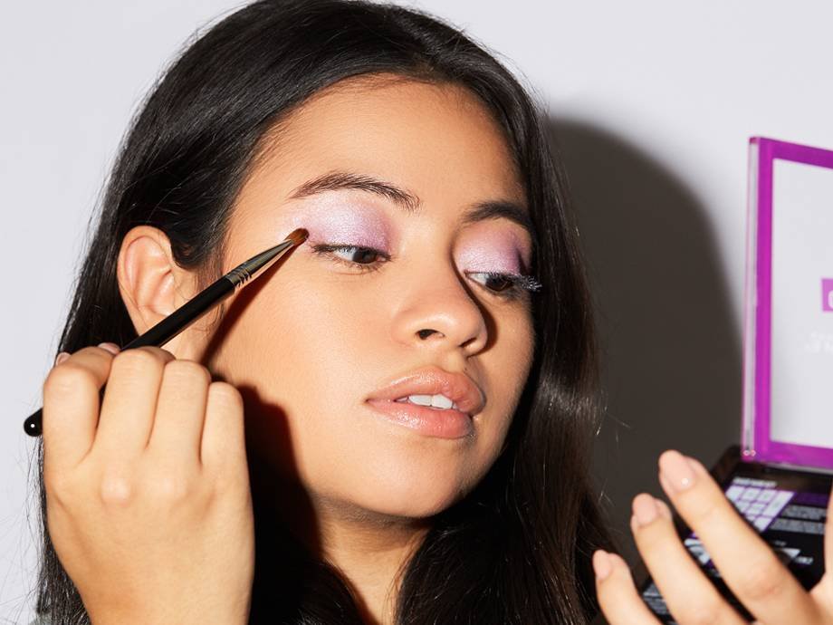person applying lavender eyeshadow to eyelid