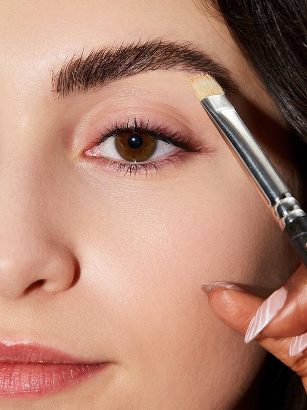 person applying makeup to eyebrow