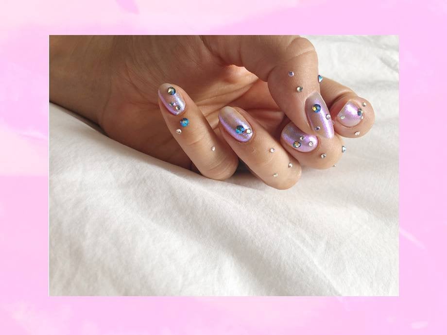 hand with nails painted light purple with silver and blue rhinestone embellishments