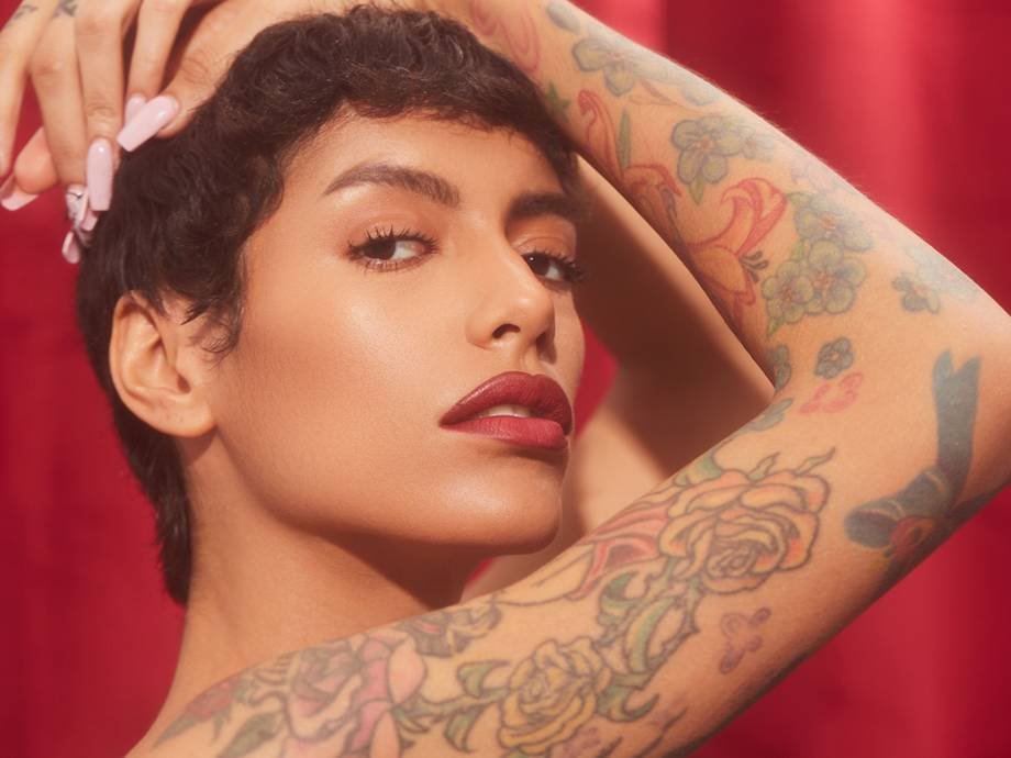 person wearing red lipstick with tattoos on arm