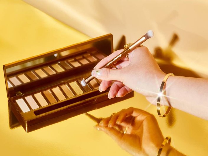 hand holding makeup brush to Urban Decay Naked Honey Palette