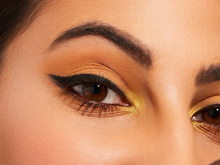 close-up of person's eye wearing nude and gold eyeshadow with black winged eyeliner