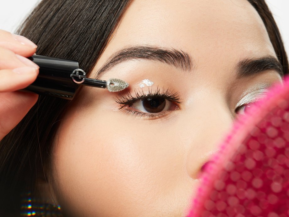close-up of person applying silver liquid eyeshadow to eyelid