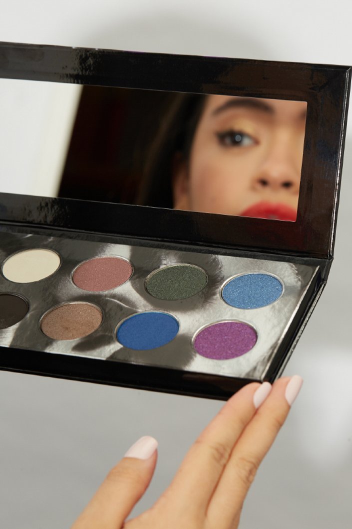person looking through mirror on eyeshadow palette