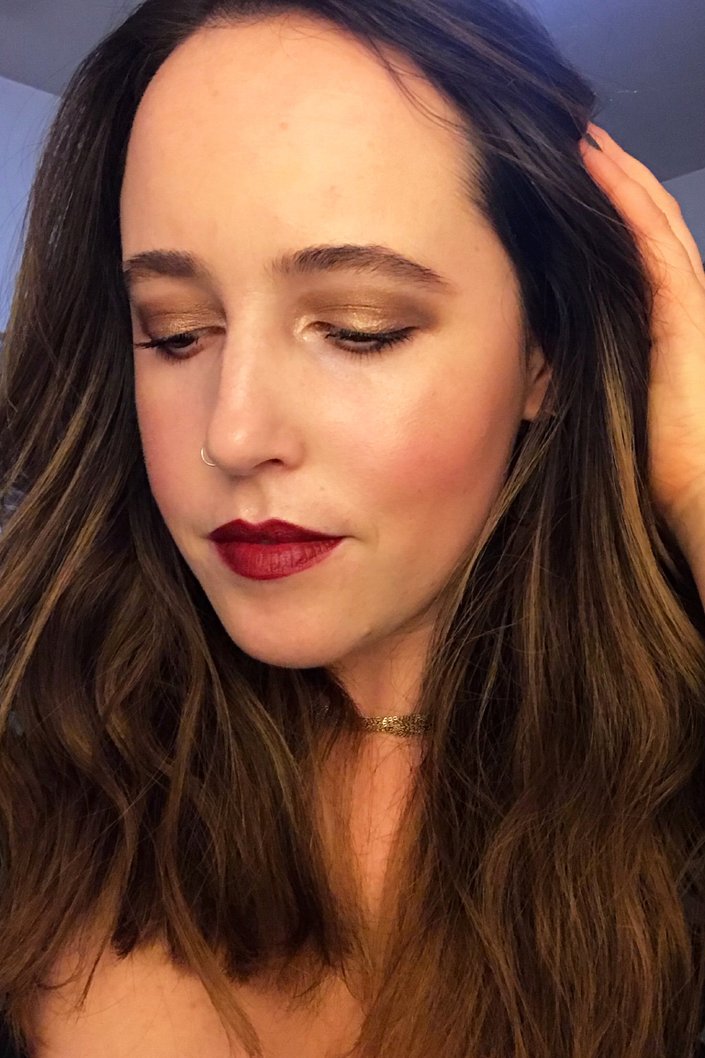 person wearing gold glitter eye makeup and dark red lipstick