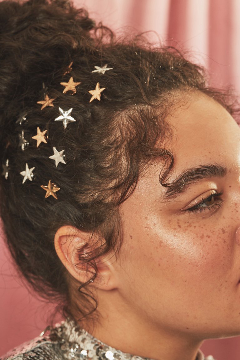 person with hair in curly bun and wearing star-shaped hair clips