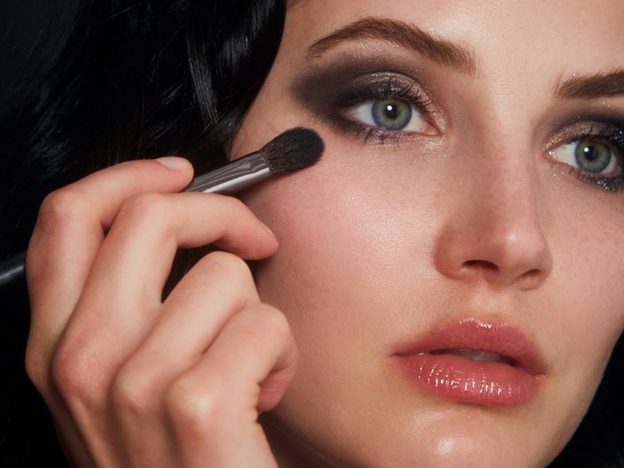 person holding makeup brush under eye