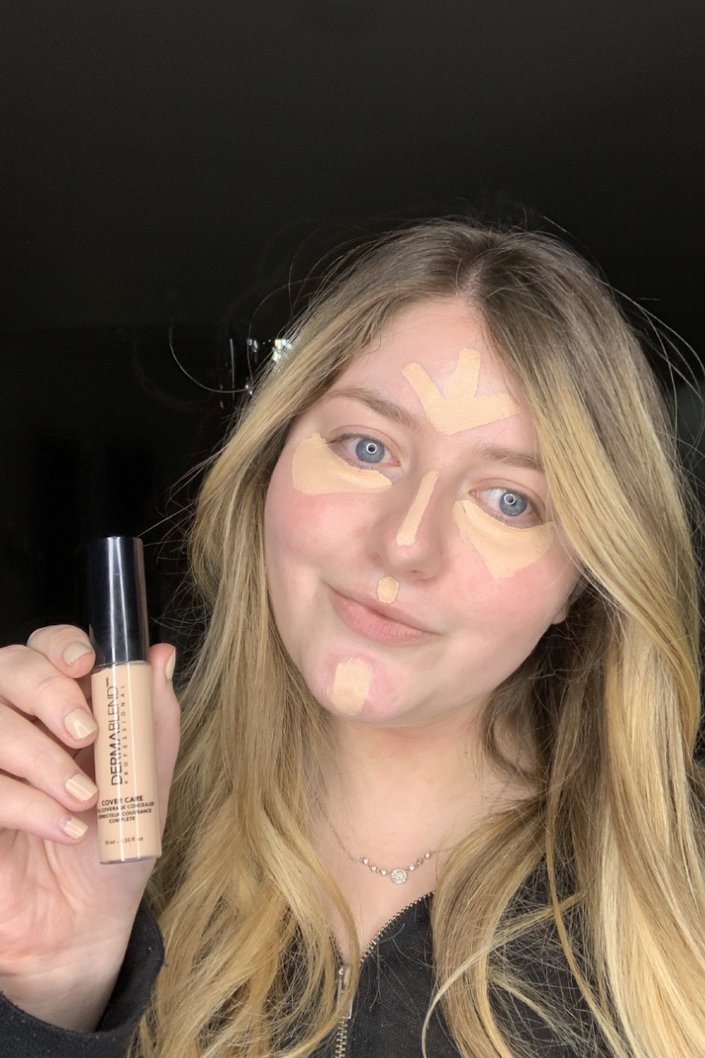 person holding Dermablend Cover Care Concealer with concealer swatches on face