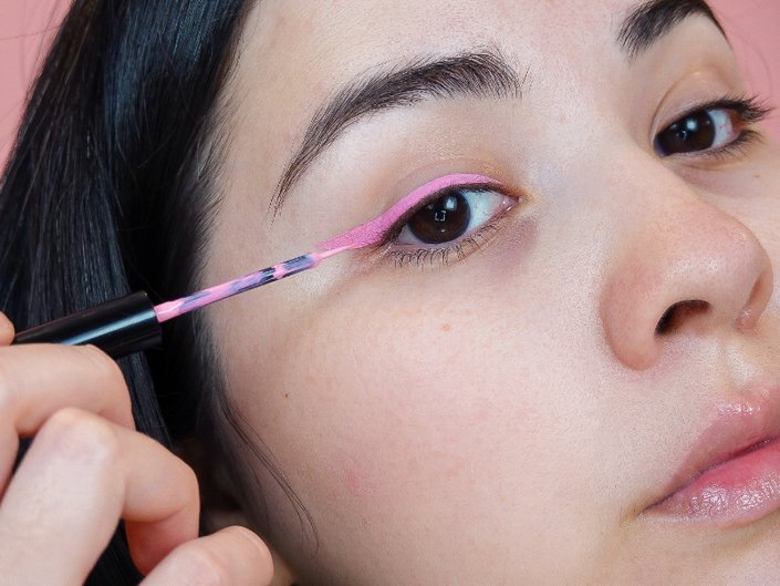 person applying pink eyeliner to eyelid