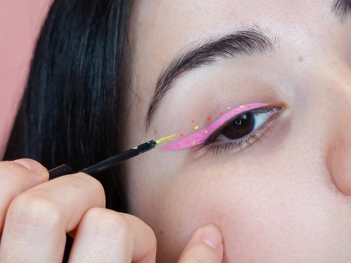 person applying multicolored dots to eyelid