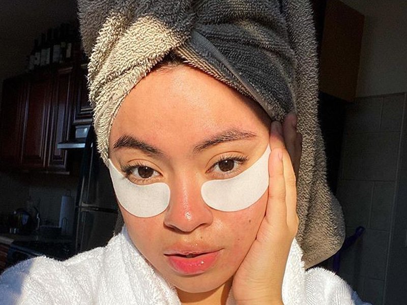 person wearing towel on head and eye mask patches under eye