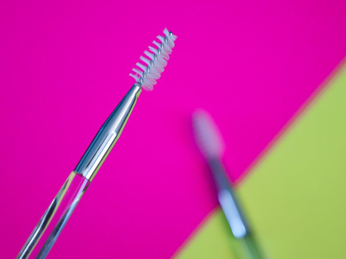 Makeup spoolie on bright pink and green background