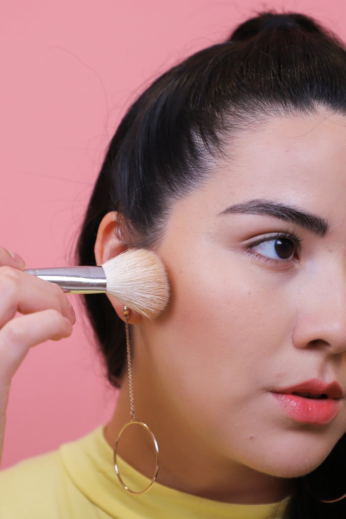 person applying makeup to cheek