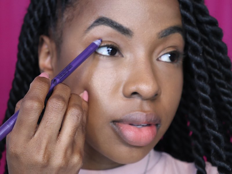 person applying purple eyeliner to eyelid