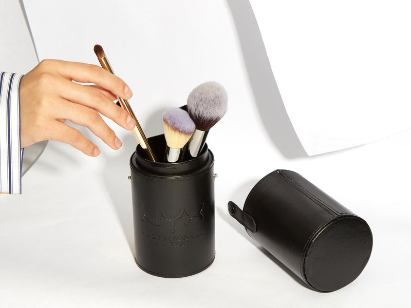 hand removing makeup brush from makeup brush set in container