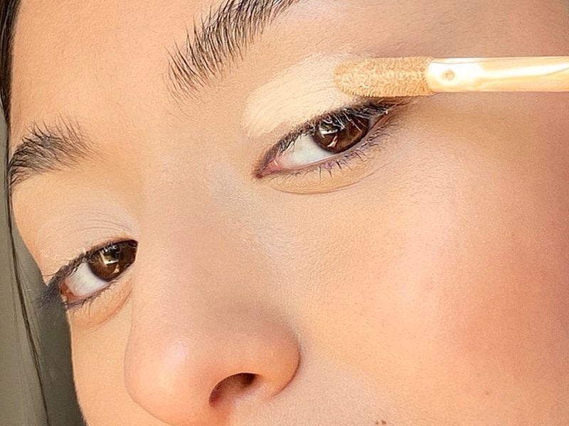 close-up of person applying concealer to eyelid