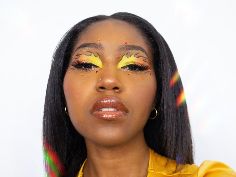 person wearing yellow and orange fire-shaped eye makeup