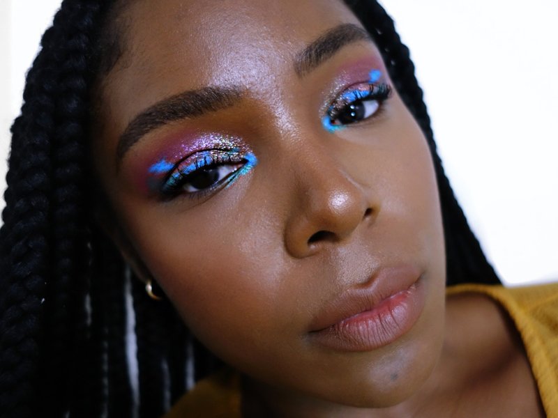 A close-up picture of a black makeup artist wearing colorful eyeshadow