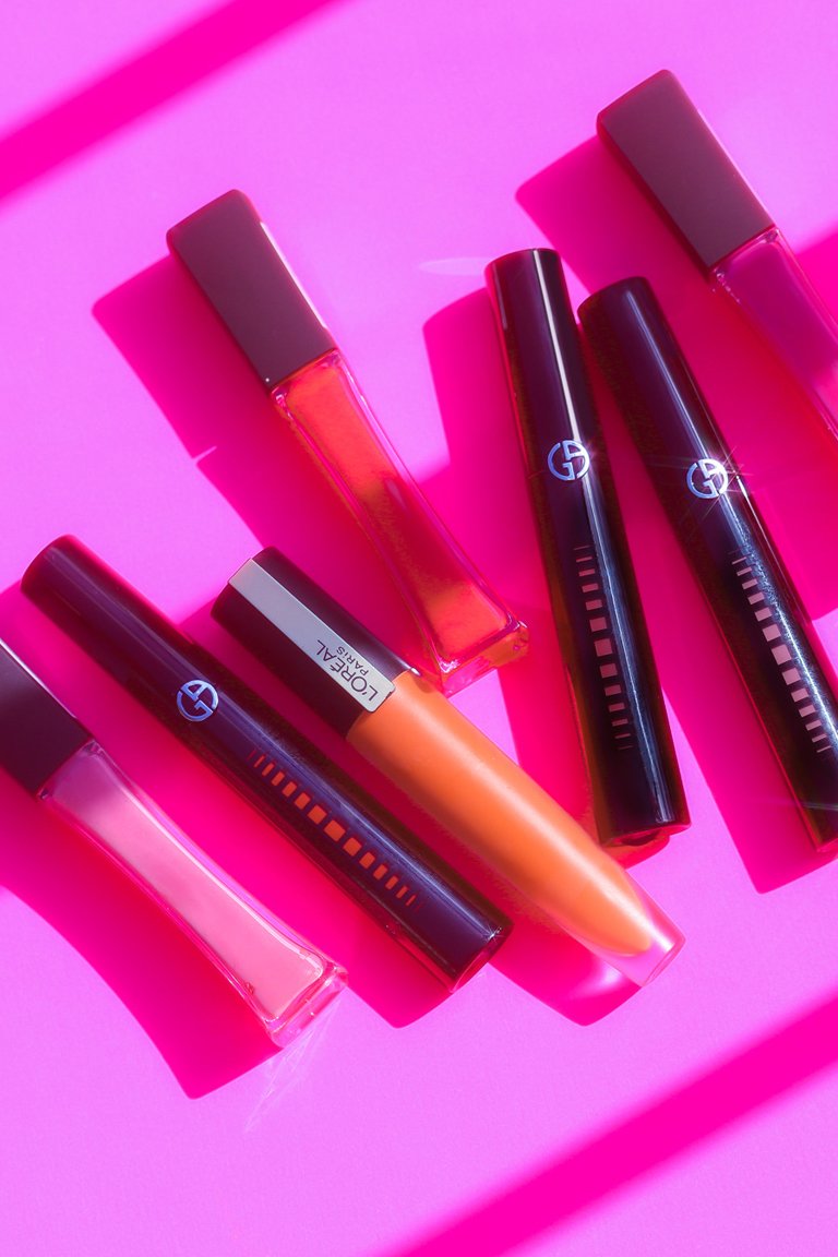 various lip gloss tubes on pink background