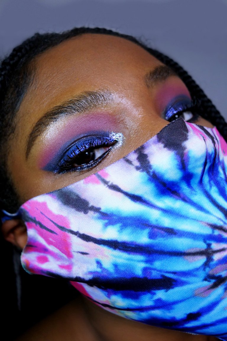 person wearing multicolored eye makeup with a protective face mask