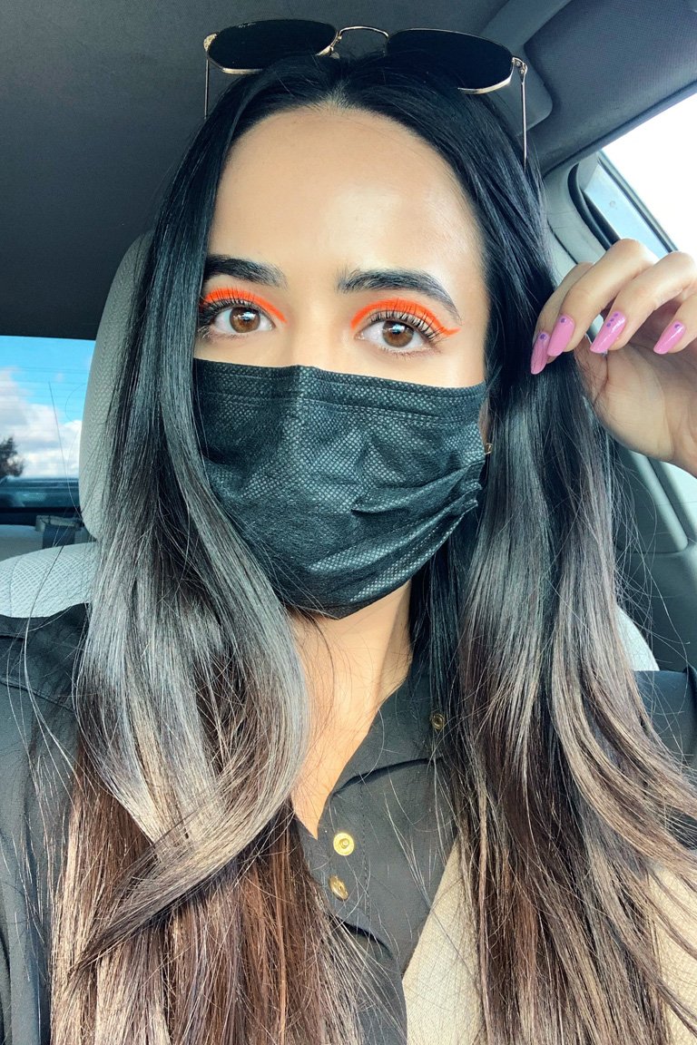person wearing orange eye makeup with a protective face mask