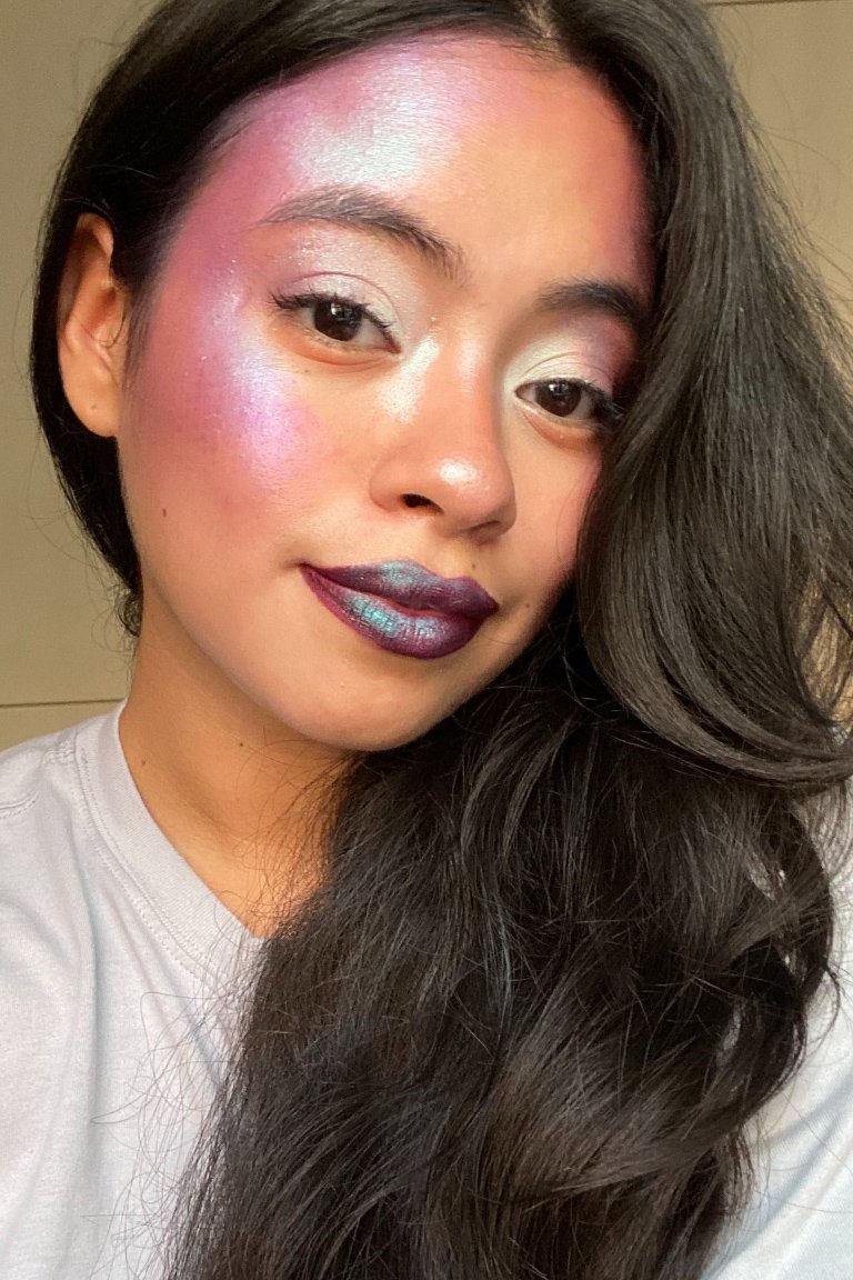 person wearing purple shimmering face makeup and purple iridescent lipstick