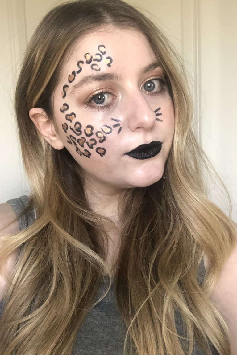 person wearing cheetah face makeup and black lipstick