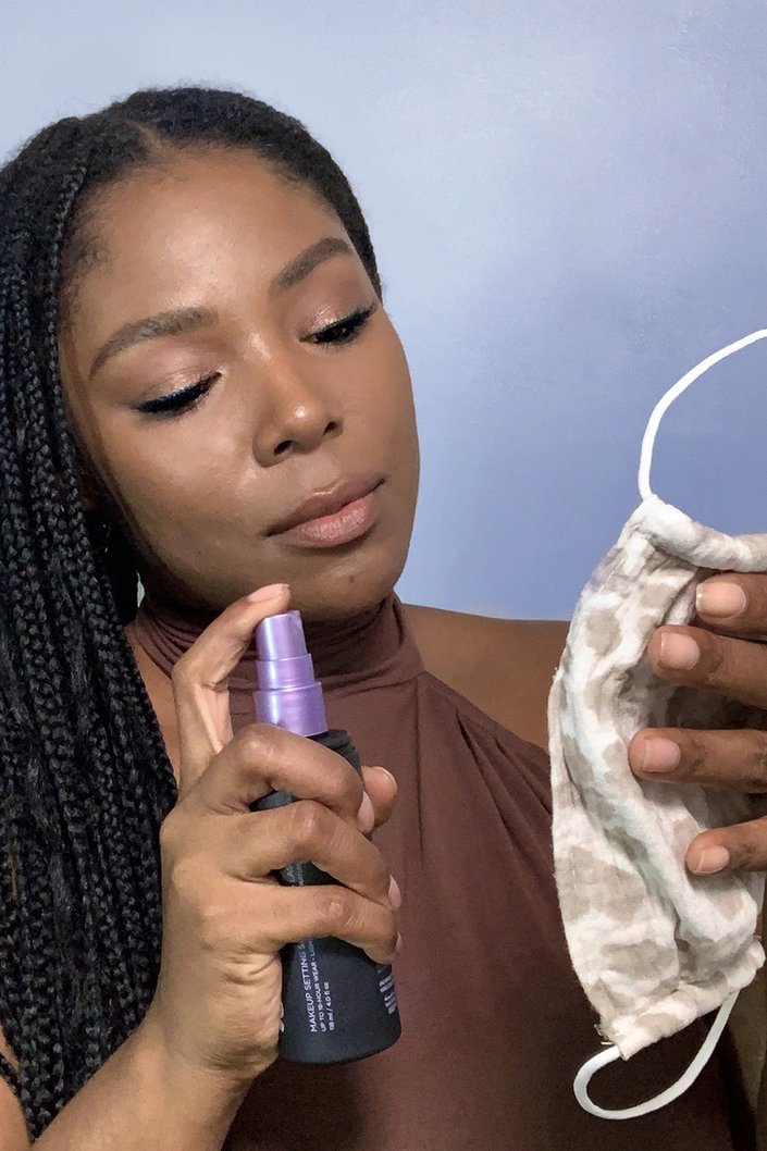 person spraying protective face mask with Urban Decay All Nighter Spray