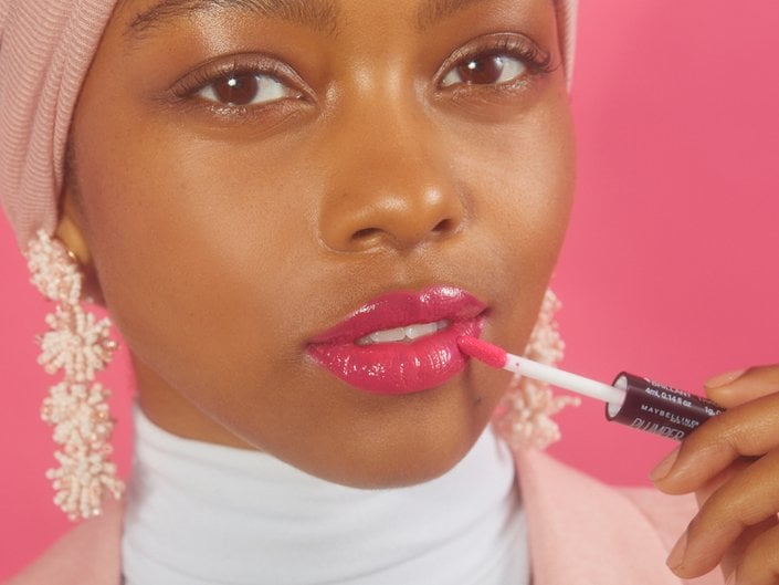 person applying pink liquid lipstick to lips