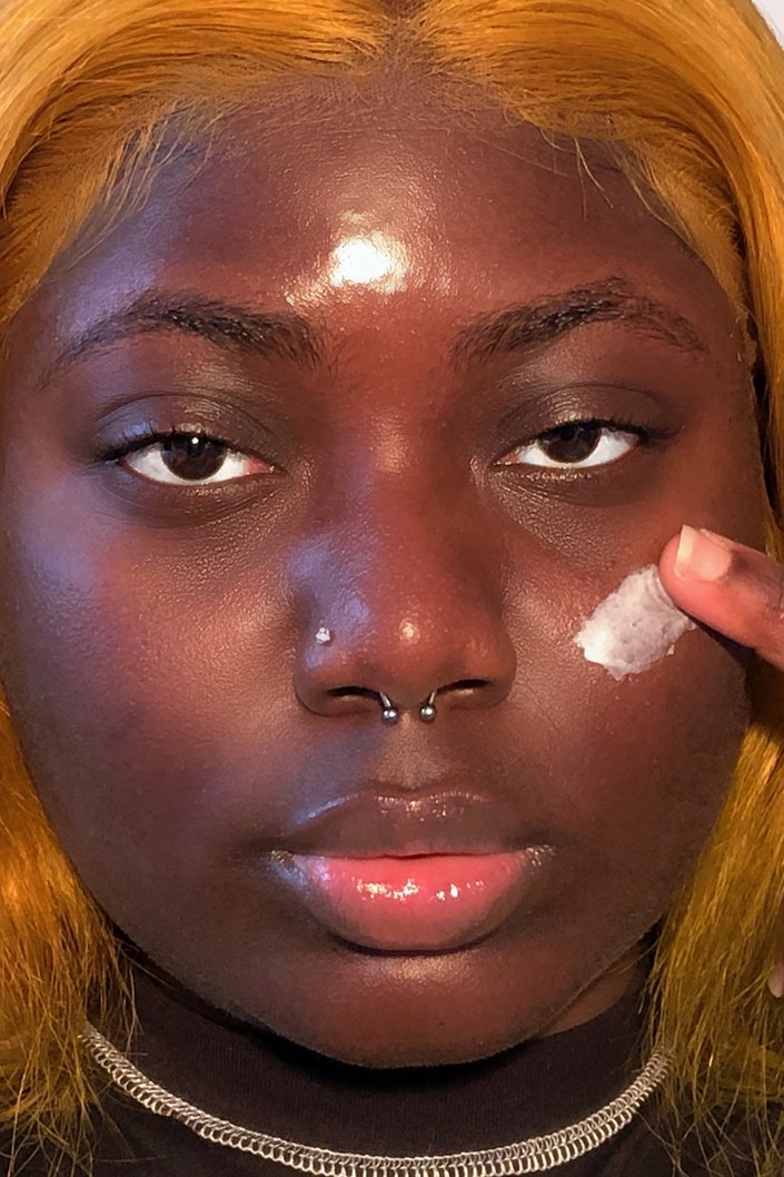 person applying moisturizer to cheek