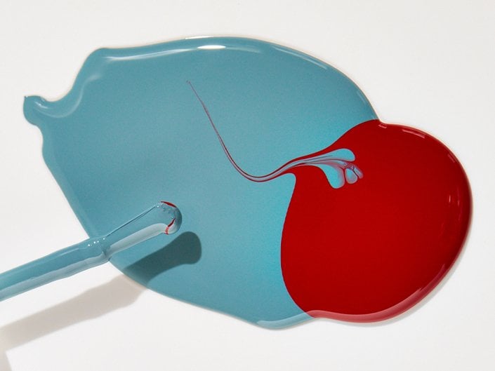 Two puddles of red and blue nail polish stains on a white surface