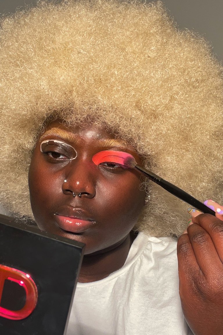person applying pink eyeshadow to eyelid
