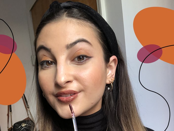 person applying brown liquid lipstick to lips