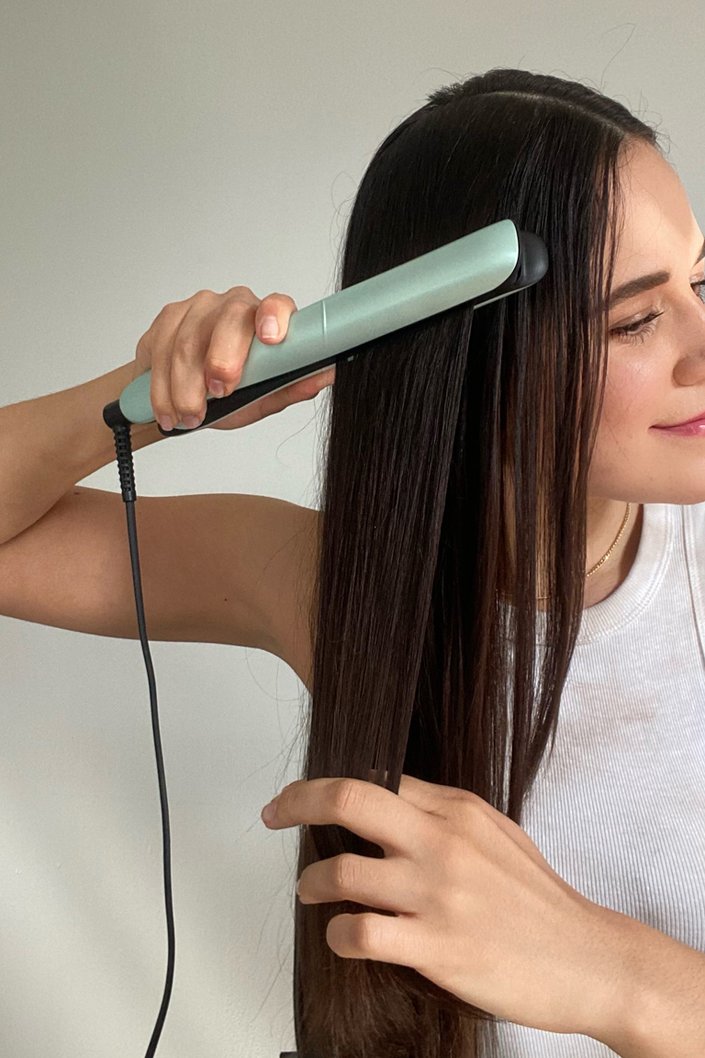 person straightening hair with flatiron