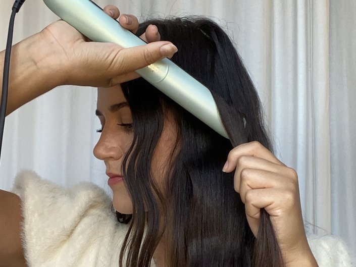 person curling hair with curling iron