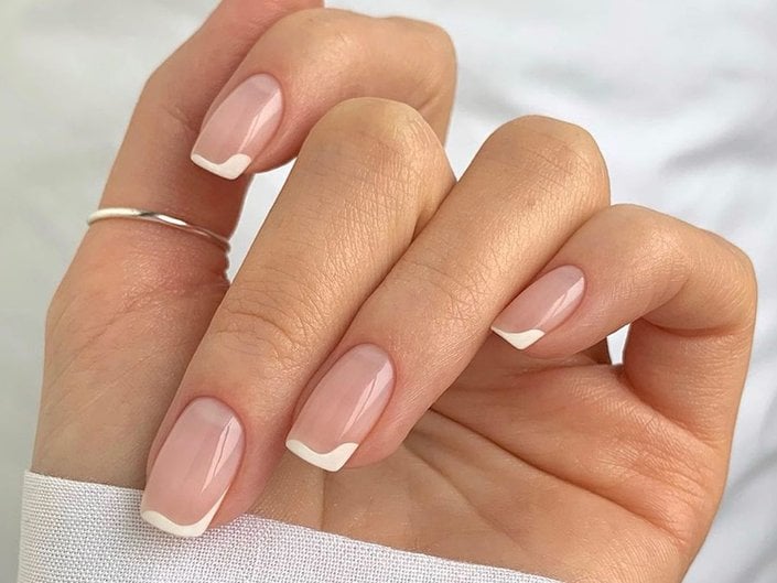hand with white french nail art on nails