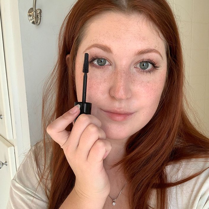 person holding mascara wand up to eyelashes