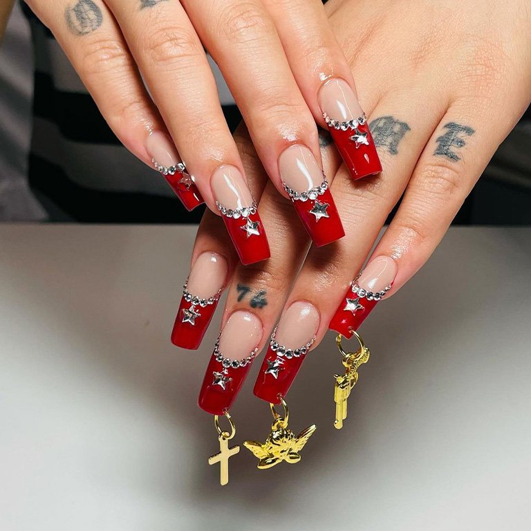 hands with red french tips and rhinestones on nails