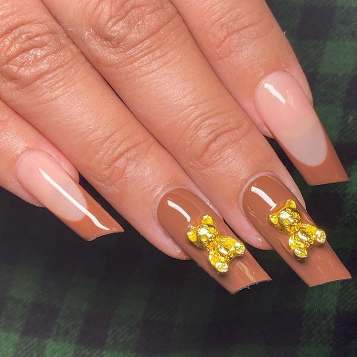 hand with brown nails polish and teddy bear accents on nails