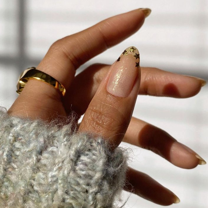 hand with golden shimmer manicure with gold stars