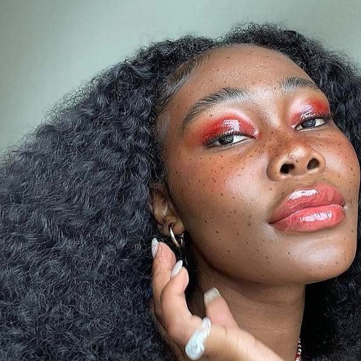 person wearing glossy red eyeshadow and lip gloss