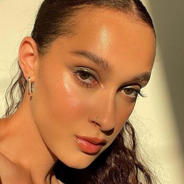 person wearing gold glitter eyeshadow and glossy makeup