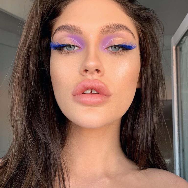 person wearing glossy lavender eyeshadow and royal blue eyelash extensions